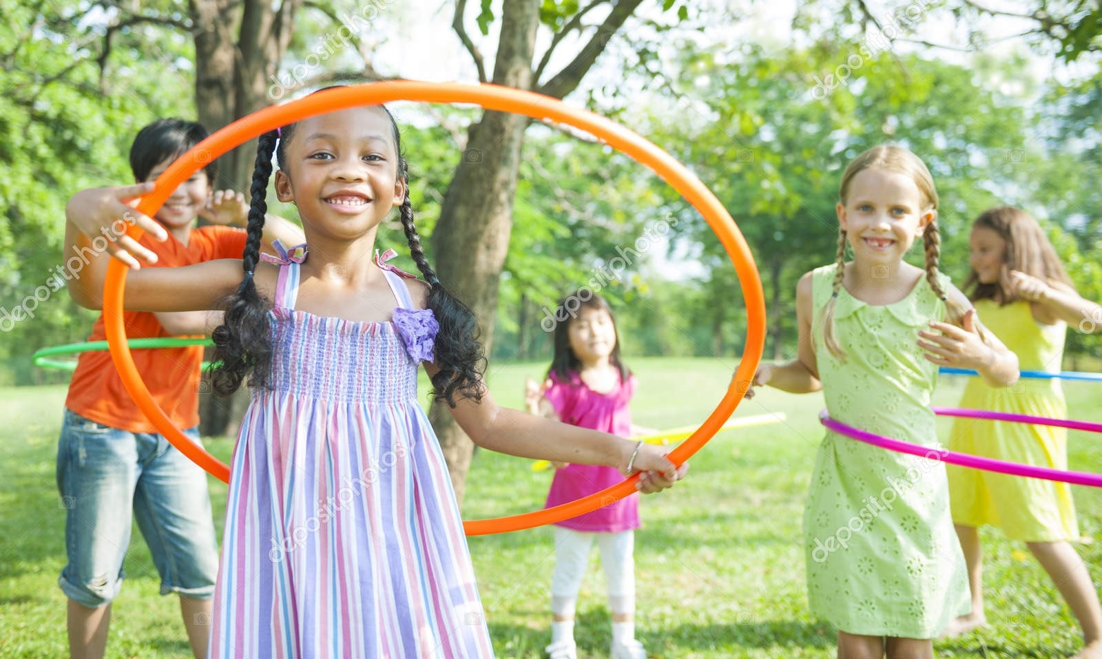 Children playing with hula hoops together outdoors in a park