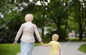 Grandmother and grandchild walking hand in hand through a park